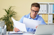 © DragonImages - Portrait of serious young businessman checking documents
