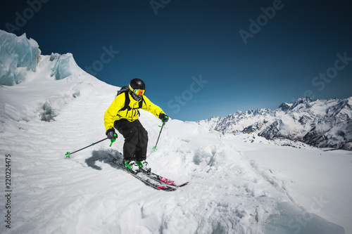 Fotografie, Obraz Professional skier at the speed before jumping from the glacier in winter agains
