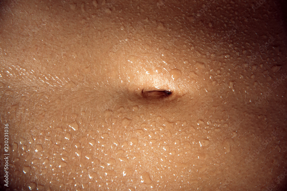 Navel. Wet stomach. A young body after a shower or sex. Sweat, hot passion. Erotic subtext. Light skin color. Young girl after sports training. Clean skin. Dermatology