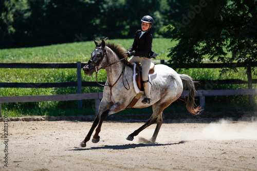 Fotografie, Obraz A girl riding a horse while competing in a horse show.