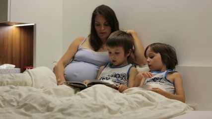 Wall Mural - Pregnant mum, reading bedtime story for her sons