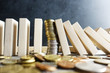Collapse of the exchange rate concept, with pile of coins between wooden pieces as domino 
