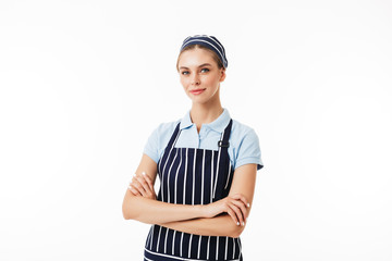 Wall Mural - Beautiful woman cook in striped apron and cap dreamily looking in camera with arms folded over white background