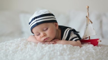 Sticker - Cute baby boy, dressed in sailor clothes, sleeping with wooden boat