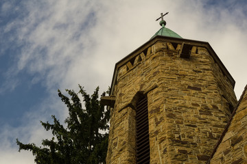 An old church tower below a cloudy summer sky