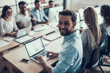 Young Smiling Businessman Working on Laptop