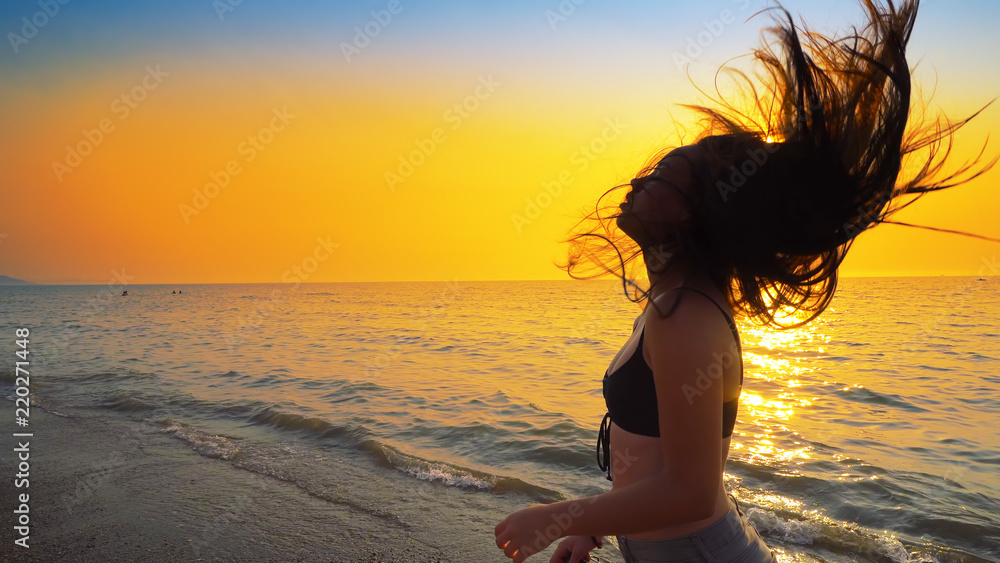 Beautiful model in swimsuit posing on the beach in sunset sunlight with ...