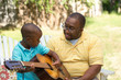 © digitalskillet1 - Father teaaching his his son to play the guitar.