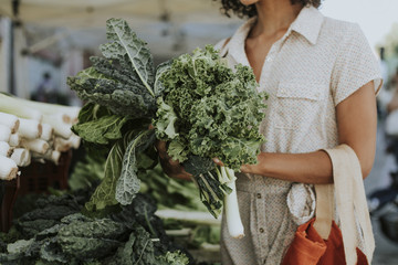 Beautiful woman buying kale at a farmers market