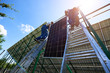 © anatoliy_gleb - Professional workers team installing solar panels on the green metal construction using different equipment. Innovative solution for energy solving. Use renewable resources. Green energy.