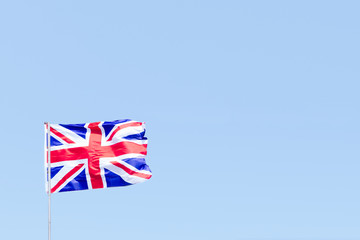 Union Jack flag of Great Britain UK Blowing in the wind against a empty blue sky