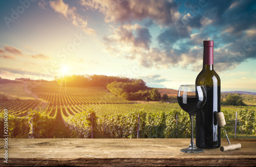 Fotografía Red wine bottle and wine glass on wodden barrel