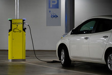 Electric Car Is Charged At The Charging Station In The Underground Parking Lot
