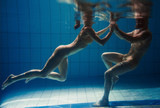 Fototapeta Tęcza - underwater portrait of the atlethic, sporty dancing and doing yoga asanas couple (man and woman) underwater in the swimming pool