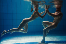 Underwater Portrait Of The Atlethic, Sporty Dancing And Doing Yoga Asanas Couple (man And Woman) Underwater In The Swimming Pool