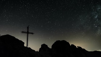 Wall Mural - stars with milky way galaxy moving over cross in top of the mountains time lapse