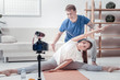 © Viacheslav Yakobchuk - Supportive trainer. Smiling sporty man helping pretty woman doing exercises streaming about sport