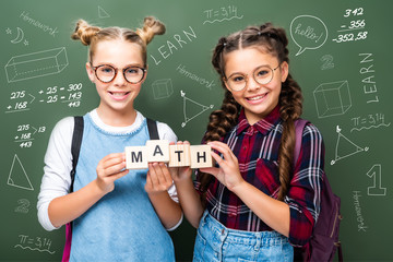 Wall Mural - schoolchildren holding wooden cubes with word math near blackboard with mathematics symbols