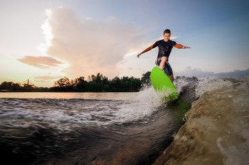 Attractive male wakeboarder riding on the green board