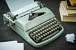 beautiful old gray typewriter, book and a piece of paper on a black wooden table