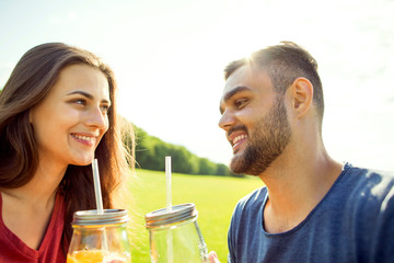 couple in love have fun in the park and drink smoothies and eating fruit at a picnic