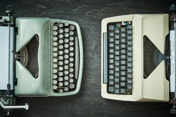 two old typewriters on a black wooden table