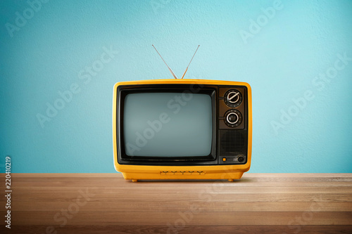 Fotografía Yellow Orange color old vintage retro Television on wood table with mint blue background