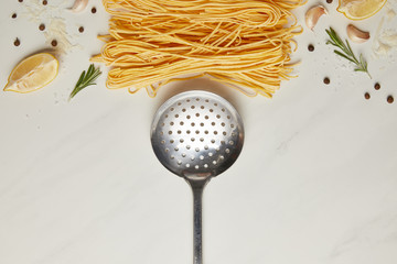 Wall Mural - top view of ladle and italian pasta ingredients on white marble tabletop