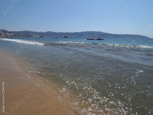 Fotografija Great landscape of sandy beach at bay of ACAPULCO city in Mexico with motor boat