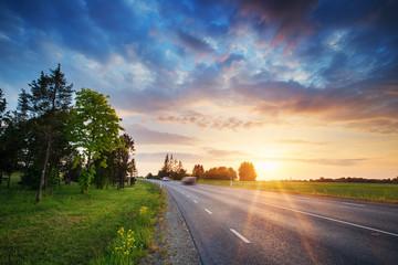 Canvas Print - black asphalt road and white dividing lines at sunset