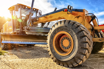 Grader leveling gravel on road construction site