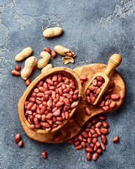 Wall Mural - Peeled peanuts in bowl and scoop on gray background. Top view of nuts.