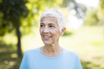 Wall Mural - Portrait of a smiling sporty senior woman in a park