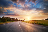 black asphalt road and white dividing lines at sunset