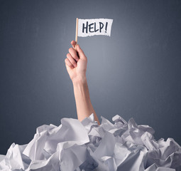 Wall Mural - Female hand emerging from crumpled paper pile holding a white flag with help written on it