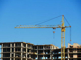 Construction site. Crane and building under construction. Unfinished concrete building.