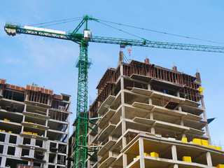 Construction site. Huge crane and concrete building against blue sky.