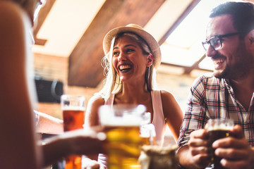 Happy friends having fun at bar - Young trendy people drinking beer and laughing together