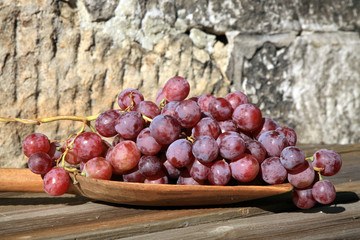 Bunch of grapes hanging on a brick wall an old, country house. An element of outdoor decoration on the occasion of a harvest festival at the end of summer.