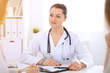 © rogerphoto - Brunette female doctor talking to patient at hospital office. Physician says about medical exams results for choosing optimal treatment. Healthcare and medicine concept