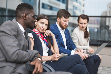 Wall Mural - Group of happy diverse male and female business people team in formal gathered around laptop computer in bright office against the background of a glass building