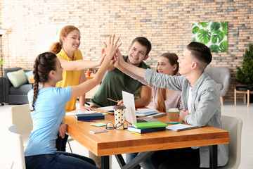 Wall Mural - Group of teenagers giving high five indoors