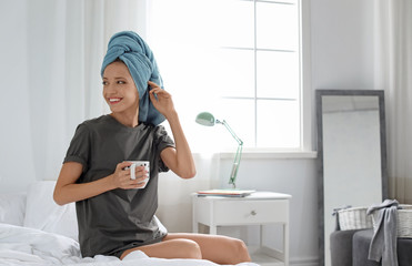 Poster - Young happy woman with cup of aromatic coffee on bed at home. Lazy morning