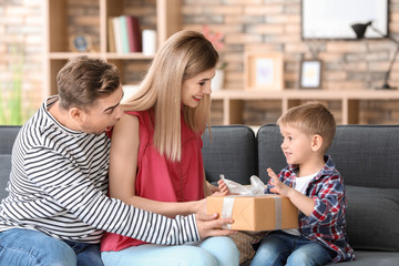 Wall Mural - Cute little boy receiving gift from parents at home