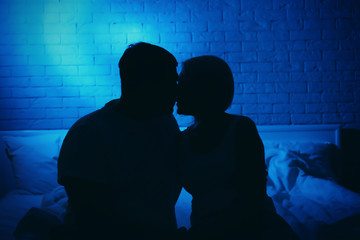 Silhouette of couple in bed at night time