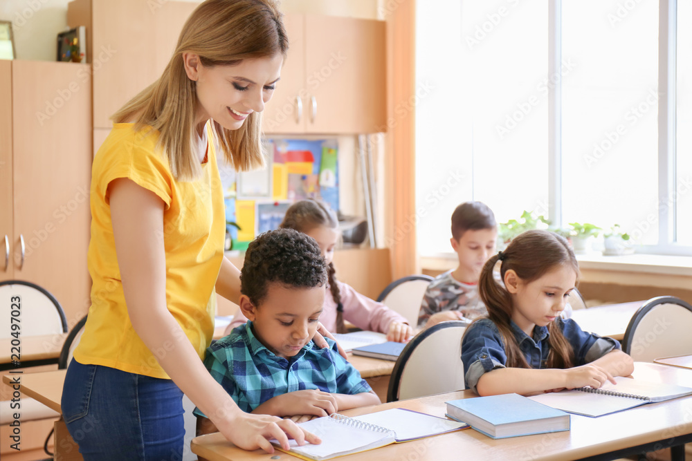 Female teacher helping boy with his homework in classroom at school