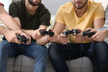 Wall Mural - Young men playing video games at home, closeup