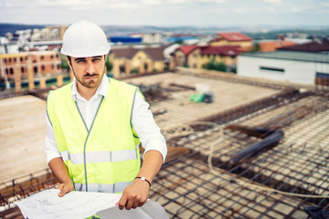 Wall Mural - engineer on construction site, portrait of man wearing hardhat and safety equipment on building site