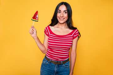 Sticker - Beautiful young woman in casual clothes with lollipop in hands posing on orange background