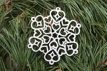 Wall Mural - Silver snowflake ornaments on green pine branches background.  Winter christmas decoration lazer cut snowflakes on  pine branches.